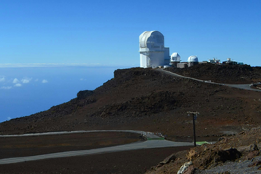 O cume de Haleakalā: cúpulas brancas de observatório sobre encosta vulcânica escura, com o mar de nuvens ao fundo.