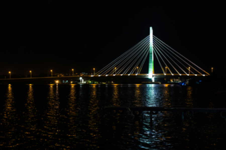 Lagos à noite: ponte estaiada iluminada refletida na água escura da lagoa.
